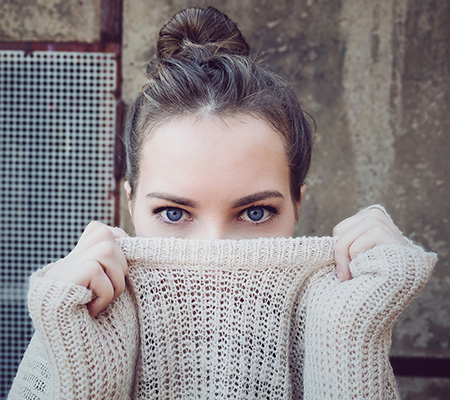 junge Frau mit einem halb über das Gesicht gezogenem Pulli