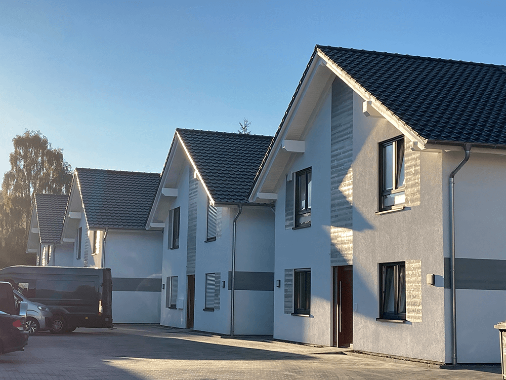 Referenz Kurmann Neugebaute Wohnhäuser mit weißer Fassade und schwarzen Dächern